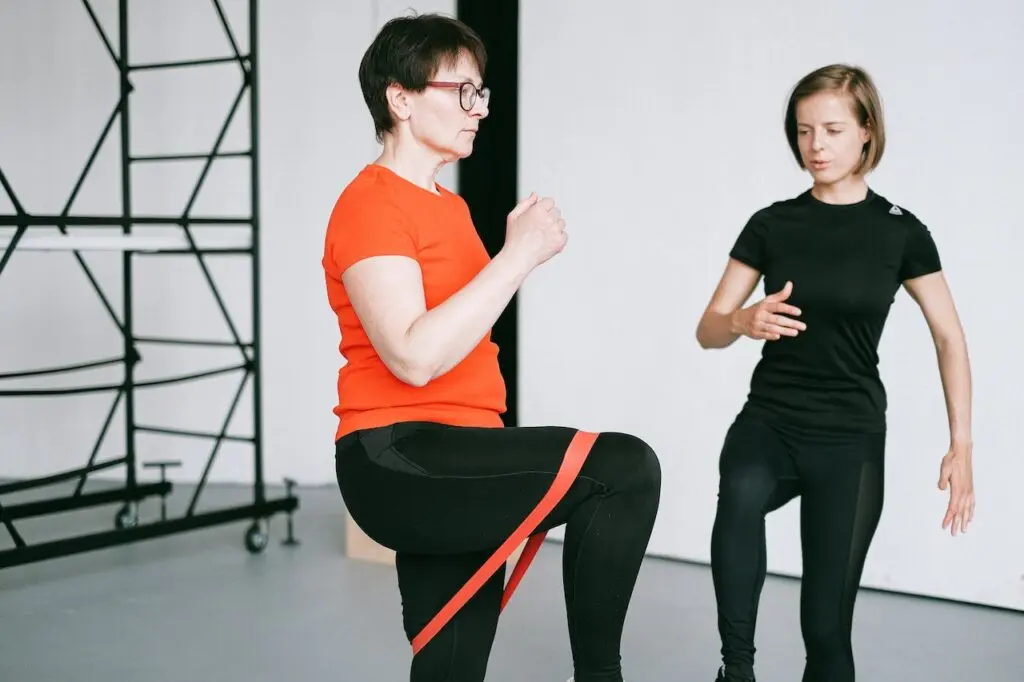 Kinetoterapeut care asistă un pacient la exerciții cu banda elastică de rezistență